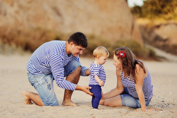Мама и папа играют со своей маленькой дочерью на пляже...