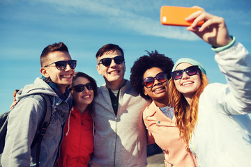 smiling friends taking selfie with smartphone