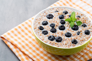 Buckwheat porridge in a bowl with mint leaves and blueberries.