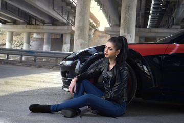 woman sitting on the pavement next to the car