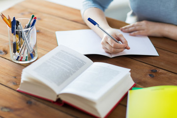 close up of student with book and notebook at home