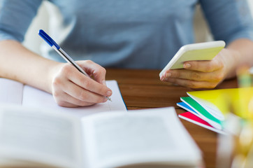 close up of student with smartphone and notebook