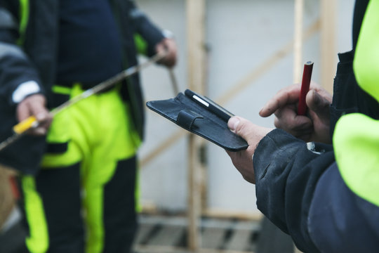 Mid-section of construction worker opening note pad