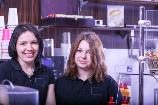 Two smiling women face behind the cafe bar counter