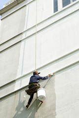painter hanging on white building.
