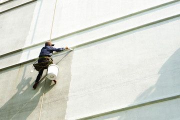 painter hanging on white building.
