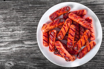 Grilled sausages on a white dish, top view