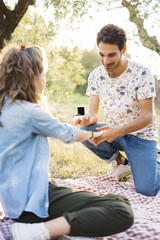 Young man proposing to his fiancee with a beautiful engagenemnt ring