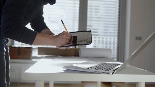 Architect working from home on computer, writing, taking notes