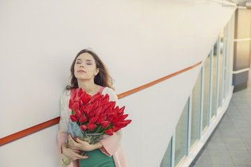 Young blond woman with a bouquet of red tulips