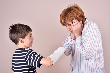 Son showing his broken arm with plaster to his mother  
