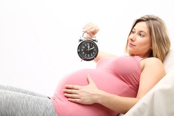 Kobieta w ciąży patrzy ma zegarek na białym tle