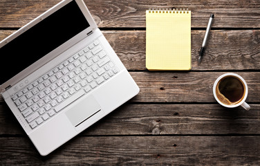 Laptop with cup of coffee and notepad 