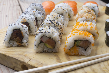 Different Sushi rolls,wasabi and ginger on a plate on wooden bac