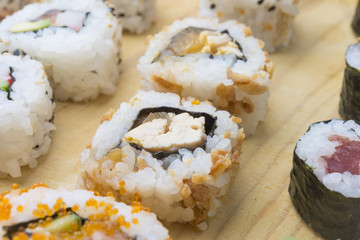 Different Sushi rolls,wasabi and ginger on a plate on wooden bac