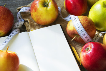 Apples with tape measure, Open notebook for notes. The concept of a healthy lifestyle and losing weight. Free space for text. Copy space. selective soft focus
