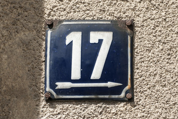 Weathered grunge square metal enameled plate of number of street address with number 17 closeup