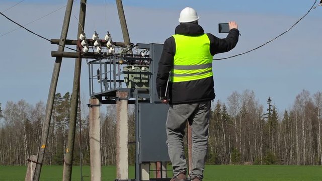 Engineer take pictures on tablet PC near power transformer 

