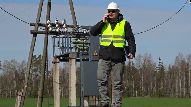 Engineer talking on smartphone near power transformer