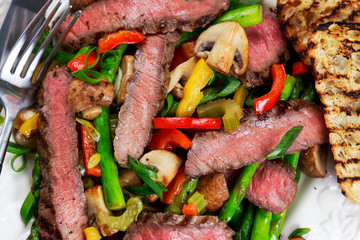 Grilled steak with stir-fried vegetables on plate.