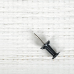 Close-up black macro thumbtack on wooden surface