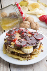 delicious pancakes with nuts, banana, strawberry and chocolate