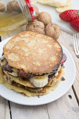 pancakes with banana, nuts and strawberry on wooden background