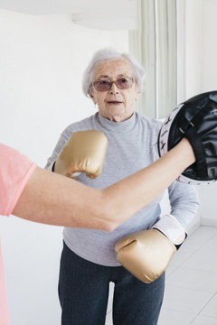 Senior woman boxing with fitness instructor