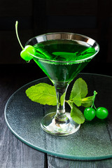 Green cocktail with maraschino cherry in a martini glass