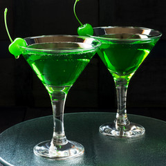 Green cocktail with maraschino cherry in a martini glasses