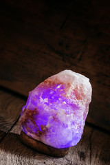 Glow salt lamp, dark vintage wooden background, selective focus