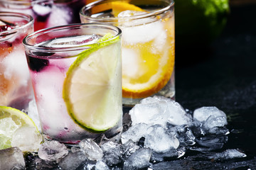 Home fizzy lemonade, fruit, ice, on a dark background, selective