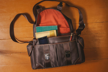 Vintage bag with old books on wooden floor
