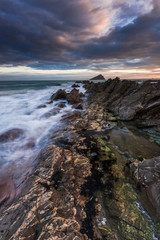 Red rocks on beach at sunset