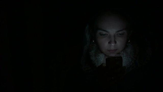 young woman uses a smartphone at night