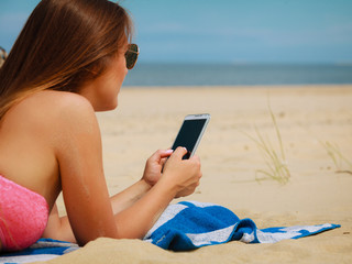 Woman on beach texting on smartphone.