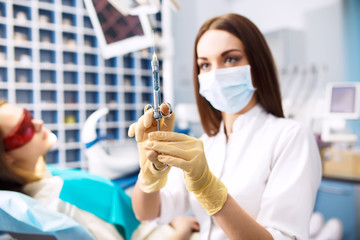 syringe. an injection. cauterized . Portrait of female dentist at office. Dental care Concept. Dental inspection is being given to Beautiful girl surrounded by dentist and his assistant
