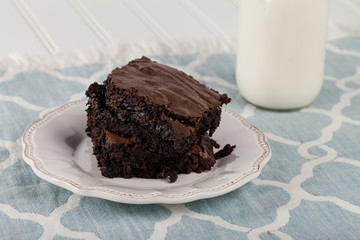 Decadent dark chocolate chip brownie with a milk jug on a blue and white place mat