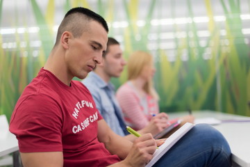 male student taking notes in classroom