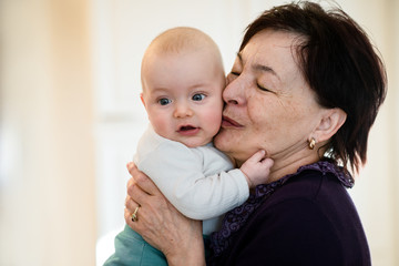 Senior woman kisses her grandchild