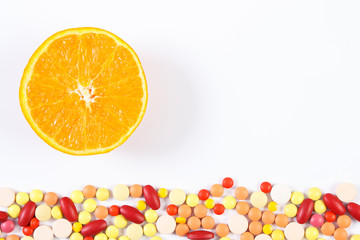 Colorful medical pills and fresh orange on white background, health care and healthy lifestyle concept, copy space for text
