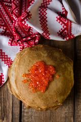 Traditional Russian pancakes with red caviar on wooden rustic background. Maslenitsa. Top view.