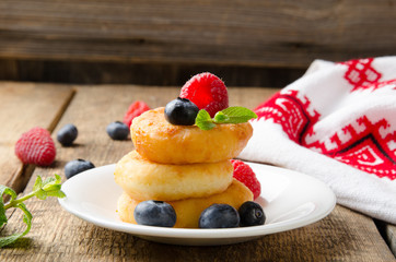 Russian cottage cheese pancakes with raspberries on wooden background. Selective focus.