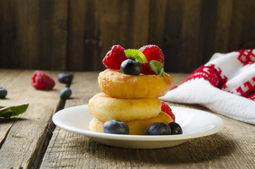 Russian cottage cheese pancakes with raspberries on wooden background. Selective focus.