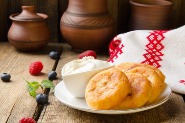 Russian cottage cheese pancakes with raspberries on wooden background. Selective focus.