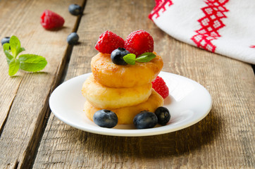 Russian cottage cheese pancakes with raspberries on wooden background. Selective focus.