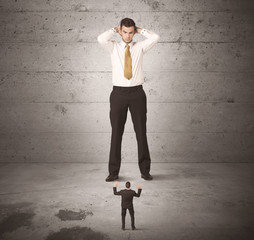 Huge business guy looking at small coworker