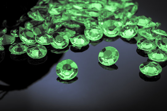 Emeralds Scattered On A Shiny Surface With Prominent Emerald In The Middle