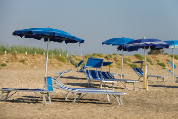 Empty deck chairs under umbrellas on the beach