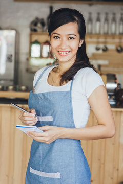 asian female waiter in apron writing order